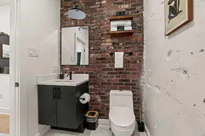a bathroom with a brick wall and a sink and a toilet at Sleep 3- Beautiful Unit- Walk Around in Old City in Philadelphia