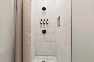 a bathroom with a shower with white marble walls at Sleep 3- Beautiful Unit- Walk Around in Old City in Philadelphia