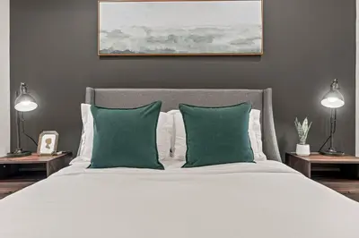 a bedroom with a white bed with two green pillows at Old City-New Building Charm-Walk to Everything! in Philadelphia