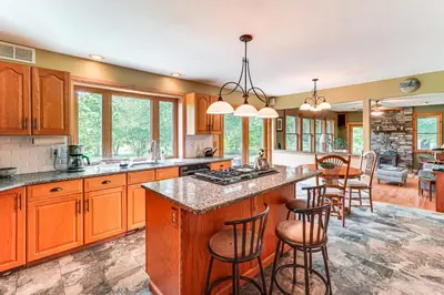 a kitchen with wooden cabinets and a island with bar stools at Peaceful Countryside Retreat with Yard in Frenchtown in Frenchtown