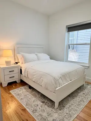 a white bedroom with a white bed and a window at Elegant Retreat Near EWR n NYC in Newark