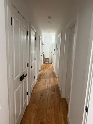 a hallway with white doors and wooden floors at Elegant Retreat Near EWR n NYC in Newark