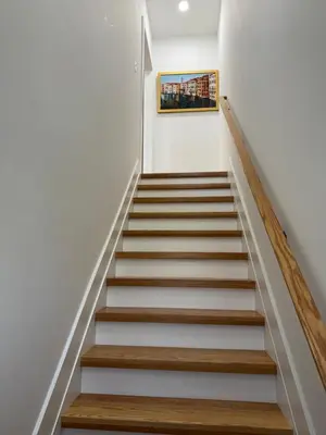a staircase in a house with white walls and wooden steps at Elegant Retreat Near EWR n NYC in Newark