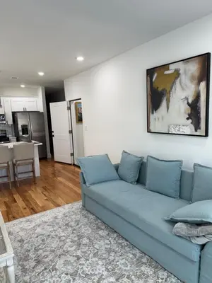 a living room with a blue couch and a kitchen at Elegant Retreat Near EWR n NYC in Newark