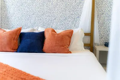 a bed with orange and blue pillows on it at Vibrant Visit 4BR, 4bath, Park 2cars FREE| 20% OFF in East Orange