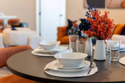 a table with plates and bowls and a vase of flowers at Vibrant Visit 4BR, 4bath, Park 2cars FREE| 20% OFF in East Orange