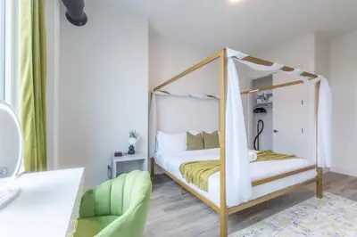 a bedroom with a canopy bed and a green chair at Vibrant Visit 4BR, 4bath, Park 2cars FREE| 20% OFF in East Orange