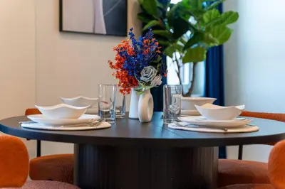 a table with plates and bowls and a vase with flowers at Vibrant Visit 4BR, 4bath, Park 2cars FREE| 20% OFF in East Orange