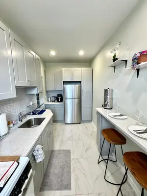 a kitchen with white cabinets and a stainless steel refrigerator at Sunny Jersey City 1BR, 25 min to NYC, 15min to EWR, King Bed, Hammock & Park Views in Jersey City