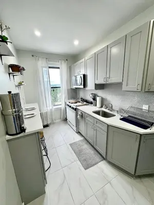 a kitchen with white cabinets and a large window at Sunny Jersey City 1BR, 25 min to NYC, 15min to EWR, King Bed, Hammock & Park Views in Jersey City