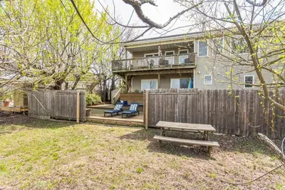 a backyard with a wooden fence and a wooden picnic table at Beach front oasis - Hot tub - Sleeps 7 in Keansburg