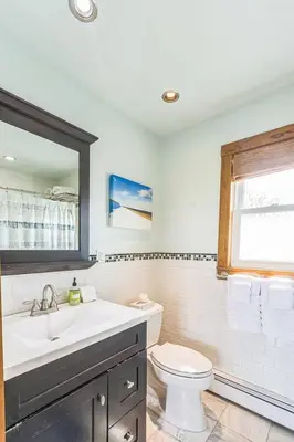 a bathroom with a sink and a toilet and a window at Beach front oasis - Hot tub - Sleeps 7 in Keansburg