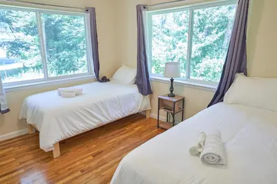 two beds in a room with two windows at Cozy Huguenot Hideaway in Huguenot