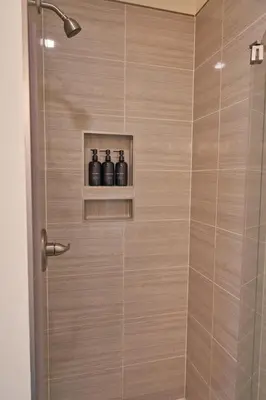 a shower with a glass door with three bottles on a shelf at Cozy Huguenot Hideaway in Huguenot
