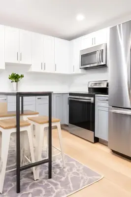 a kitchen with white cabinets and a table and chairs at Modern 2BR Cozy City Retreat Free Parking in Philadelphia