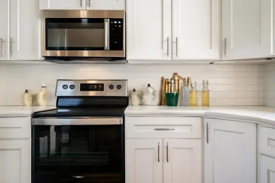 a kitchen with white cabinets and a stove and a microwave at Modern 2BR&2BAQueen BedWork DeskWiFiWD in Philadelphia
