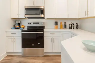 a kitchen with white cabinets and a black oven and microwave at Modern 2BR&2BAQueen BedWork DeskWiFiWD in Philadelphia