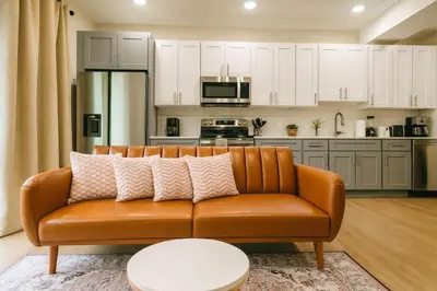 an orange couch in a living room with a kitchen at 1Bed1Bath-CentralKingBed,WD,WIFI in Philadelphia