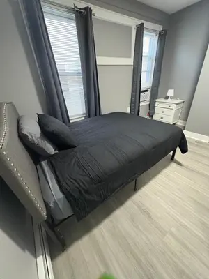 a bed in a room with a chair and a window at 4 bedroom apartment by Ewr Airport in Newark