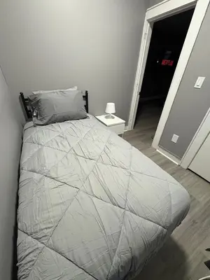 a bedroom with a bed with a gray comforter at 4 bedroom apartment by Ewr Airport in Newark