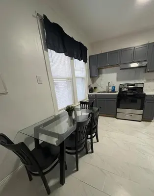 a kitchen with a glass table and chairs in it at 4 bedroom apartment by Ewr Airport in Newark