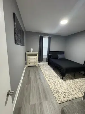 a bedroom with a bed and a dresser and a window at 4 bedroom apartment by Ewr Airport in Newark