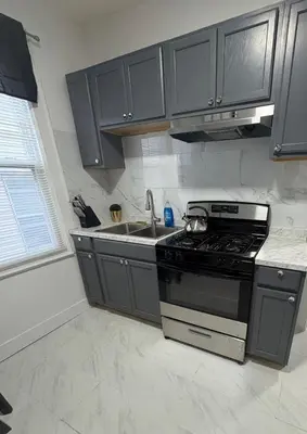 a kitchen with black cabinets and a stove and a sink at 4 bedroom apartment by Ewr Airport in Newark