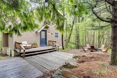 a cabin with a wooden deck in the woods at Lake Access at Family-Friendly Home in Tobyhanna in Tobyhanna
