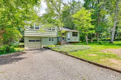 a green house with a garage in a yard at 1 Mi to Campus Princeton Home with Furnished Deck in Princeton