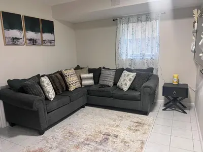 a living room with a black couch and a window at Haven 2 Bedroom by EWR airport in Newark