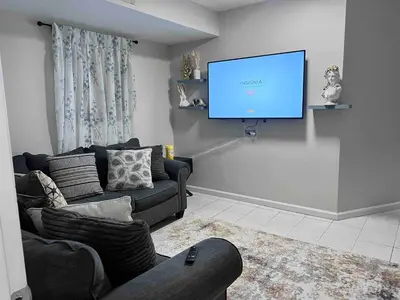 a living room with a couch and a flat screen tv at Haven 2 Bedroom by EWR airport in Newark