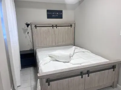a small bed in a room with a sign on the wall at Haven 2 Bedroom by EWR airport in Newark