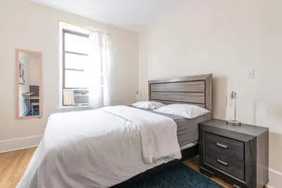 a white bedroom with a large bed and a window at 5 Bedroom 2 Bath Full Floor Midtown in New York