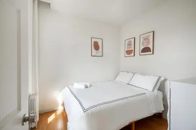 a white bedroom with a bed and pictures on the wall at Beautiful 3 Bedroom Unit in Prime Location in New York