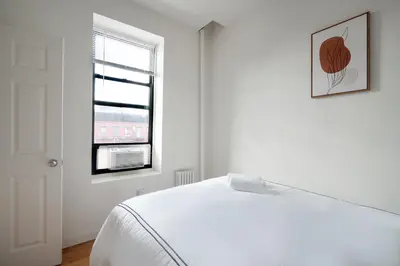 a white bedroom with a bed and a window at Beautiful 3 Bedroom Unit in Prime Location in New York