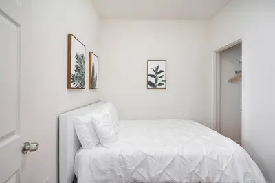 a white bedroom with a bed and two pictures on the wall at Beautiful 3 Bedroom Unit in Prime Location in New York