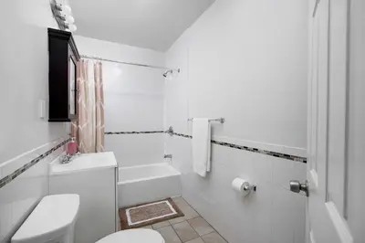 a white bathroom with a toilet and a sink at Beautiful 3 Bedroom Unit in Prime Location in New York