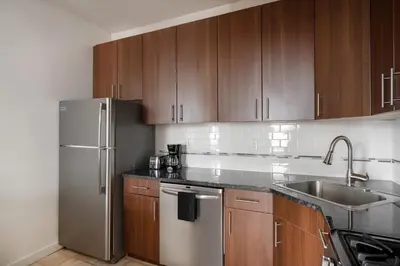 a kitchen with wooden cabinets and a stainless steel refrigerator at Beautiful 3 Bedroom Unit in Prime Location in New York