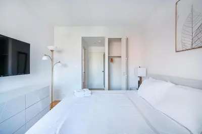a white bedroom with a white bed and a tv at Sunny 3 BR 1 Bath Apartment in NYC in New York