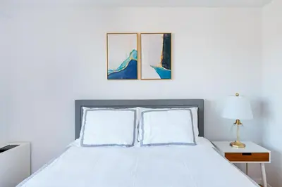 a bedroom with a white bed with two pictures on the wall at Sunny 3 BR 1 Bath Apartment in NYC in New York