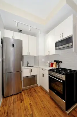a kitchen with white cabinets and a stainless steel refrigerator at Comfy 1 Bed 1 Bath Apartment in NYC in New York
