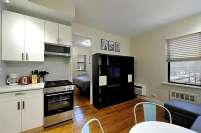 a kitchen with white cabinets and a black refrigerator at Comfy 1 Bed 1 Bath Apartment in NYC in New York