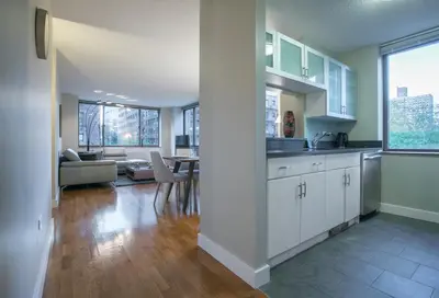 a kitchen with white cabinets and a living room at Fully Furnished 2BR 2Bath Unit in NYC in New York