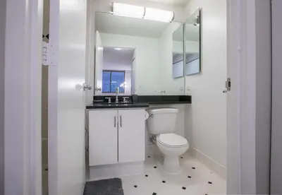 a white bathroom with a toilet and a sink at Fully Furnished 2BR 2Bath Unit in NYC in New York