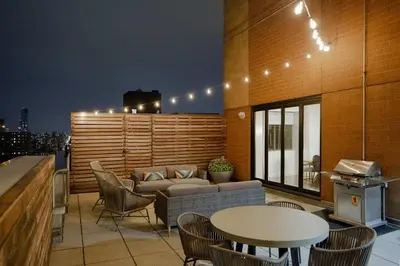 a rooftop patio with a couch and a table and chairs at Fully Furnished 2BR 2Bath Unit in NYC in New York