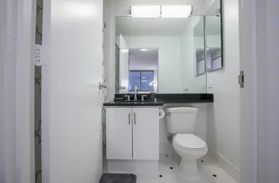 a white bathroom with a toilet and a mirror at Fully Furnished 2BR 2Bath Unit in NYC in New York