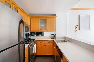 a kitchen with wooden cabinets and a stainless steel refrigerator at Contemporary 2 Bed 2 Bath Apt Bright and Sunny in New York
