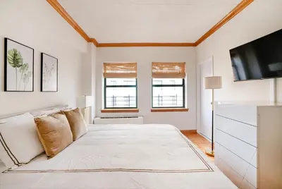 a white bedroom with a bed and a flat screen tv at Contemporary 2 Bed 2 Bath Apt Bright and Sunny in New York