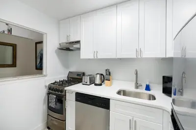 a kitchen with white cabinets and a sink and a stove at Amazing Apartment for 2 1 Bed 1 Bath in New York