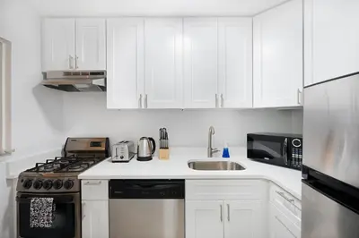 a white kitchen with white cabinets and a sink at Amazing Apartment for 2 1 Bed 1 Bath in New York